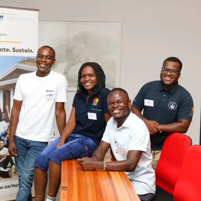 Four people in front of a Mastercard Foundation banner